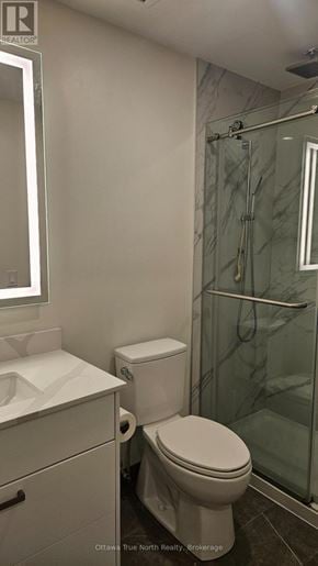 Ottawa multi-family for rent - A white toilet in a bathroom with a glass shower door.