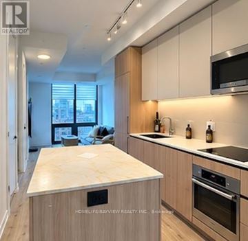 Toronto (Waterfront Communities) condo for rent - A kitchen with wooden cabinets and a marble countertop.