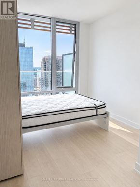 Toronto (Church-Yonge Corridor) condo for rent - A bedroom with a large bed and a window overlooking a cityscape.