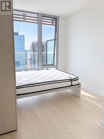 Toronto (Church-Yonge Corridor) condo for rent - A bedroom with a large bed and a window overlooking a cityscape.