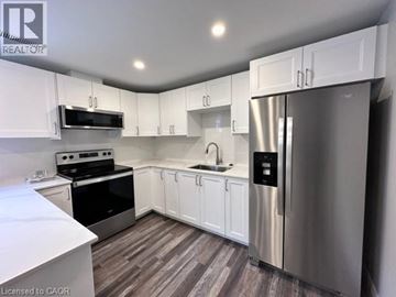 Kitchener apartment for rent - A kitchen with white cabinets and a stainless steel refrigerator.