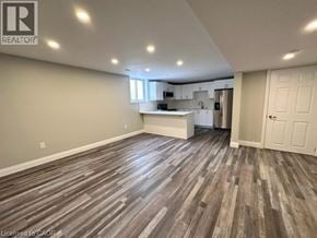 Kitchener apartment for rent - A spacious room with wood flooring and a kitchen area in the background.