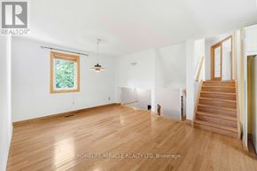 Oshawa (Samac) apartment for rent - A spacious room with wooden flooring and a staircase leading to another room.