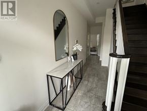 King (Nobleton) townhouse for rent - A hallway with a mirror and a console table with flowers on it.