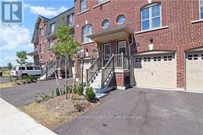 Brampton (Northwest Brampton) townhouse for rent - A brick building with a white garage door and a tree in front.