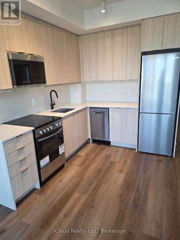 Milton (Tm Timberlea) condo for rent - A kitchen with wooden cabinets and a stainless steel refrigerator.