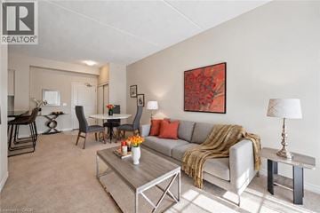 Guelph condo for rent - A living room with a grey couch, a coffee table, and a painting on the wall.