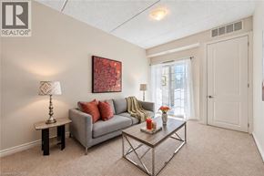 Guelph condo for rent - A living room with a grey couch, a table with a lamp and a painting on the wall.