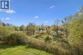 Guelph condo for rent - A fenced green area with trees and a house in the distance.