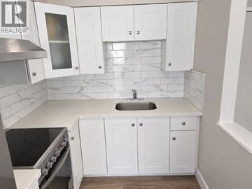 Vancouver apartment for rent - A kitchen with white cabinets and a marble backsplash.