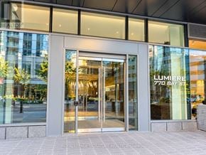 Toronto (Bay Street Corridor) condo for rent - The entrance to a building with a glass door and a sign that reads "LUMIERE 770 BAY ST".