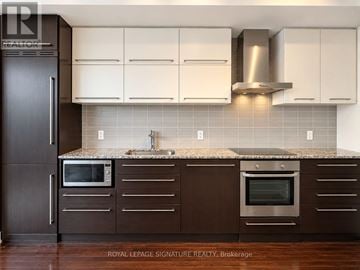 Toronto (Bay Street Corridor) condo for rent - A kitchen with brown cabinets and a black refrigerator.