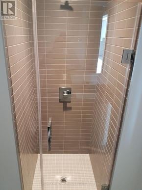 Toronto (Bay Street Corridor) condo for rent - A tiled shower stall with a door and a drain.
