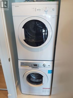 Toronto (Bay Street Corridor) condo for rent - A white front loading washing machine with a black door is in a room.