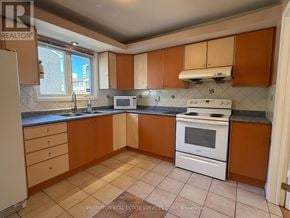 Toronto (L'amoreaux) townhouse for rent - A kitchen with a white stove top oven and brown cabinets.