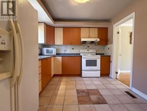Toronto (L'amoreaux) townhouse for rent - A kitchen with brown cabinets and a white stove top oven.
