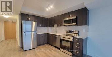 Pickering (Bay Ridges) condo for rent - A modern kitchen with dark wood cabinets and stainless steel appliances.