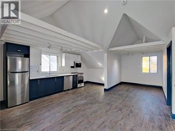 Hamilton apartment for rent - A spacious kitchen with a refrigerator, cabinets, and a window.