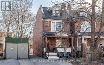 Toronto (High Park North) triplex for rent - A brick house with a green roof and a white garage door.