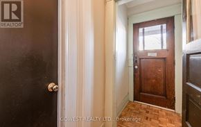 Toronto (High Park North) triplex for rent - A hallway with a wooden door and a sign that says Brokerage.