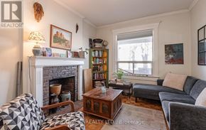 Toronto (High Park North) triplex for rent - A living room with a fireplace, couches, and a bookshelf.