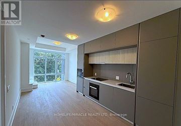 Toronto (Playter Estates-Danforth) condo for rent - A kitchen with a sink, stove, and oven with a window in the background.
