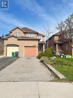 Mississauga (Central Erin Mills) apartment for rent - A house with a brown garage door is in front of a tree.