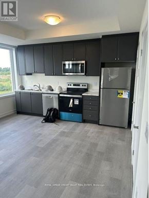 Cobourg townhouse for rent - A kitchen with black cabinets and a grey fridge.
