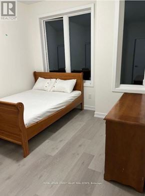 Cobourg townhouse for rent - A bedroom with a bed, nightstand, and mirror.