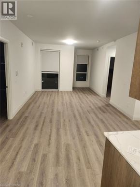 Kitchener condo for rent - A room with wooden flooring and white walls, with a window and a door visible.