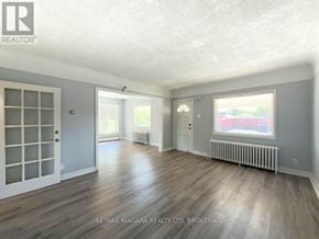 Niagara Falls (Clifton Hill) apartment for rent - A spacious room with wooden floors and white walls.
