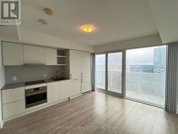 Toronto (Waterfront Communities) condo for rent - A spacious kitchen with white cabinets and a view of the city.