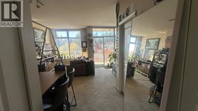 Burnaby apartment for rent - A living room with a couch, chairs, and a large window overlooking a forest.
