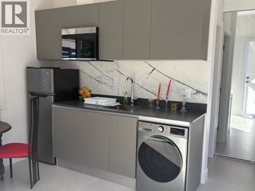 West Vancouver apartment for rent - A modern kitchen with a washing machine and microwave built into the cabinetry.