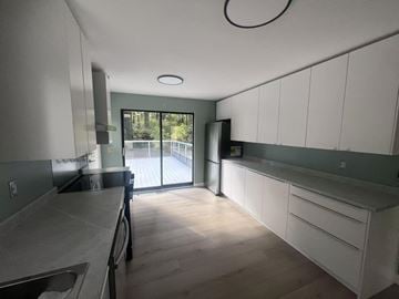 Surrey apartment for rent - A kitchen with white cabinets and a black fridge.