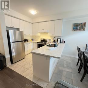 Thorold (Rolling Meadows) townhouse for rent - A kitchen with white cabinets and a stainless steel refrigerator.