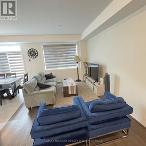Thorold (Rolling Meadows) townhouse for rent - A living room with a blue couch and a clock on the wall.