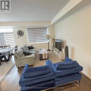 Thorold (Rolling Meadows) townhouse for rent - A living room with a blue couch and a clock on the wall.