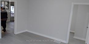 St. Catharines (Downtown) duplex for rent - A realtor is showing a room with white walls and a wooden floor.