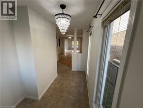 Kitchener apartment for rent - A long hallway with a chandelier and windows on the side.
