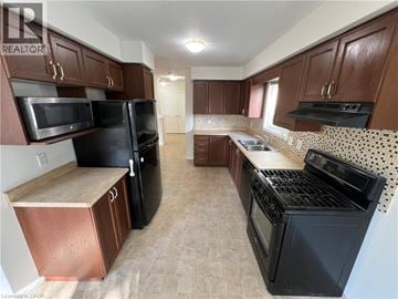 Kitchener apartment for rent - A kitchen with black appliances and brown cabinets.