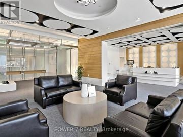 Toronto (Bendale) condo for rent - A living room with black leather furniture and a wooden accent wall.