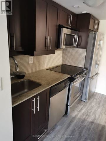 Toronto (Niagara) condo for rent - A kitchen with dark brown cabinets and a stainless steel dishwasher.