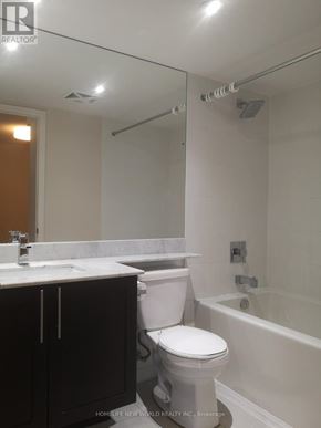 Toronto (Niagara) condo for rent - A white toilet sits in a bathroom with a white tub and sink.