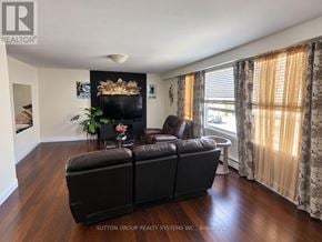 Toronto (Keelesdale-Eglinton West) townhouse for rent - A black leather sofa in a living room with a fireplace and wooden floors.