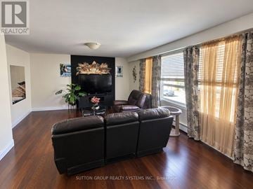 Toronto (Keelesdale-Eglinton West) townhouse for rent - A black leather sofa in a living room with a fireplace and wooden floors.