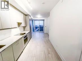 Mississauga condo for rent - A kitchen with white cabinets and a view of a cityscape through a glass door.