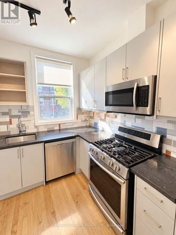 Toronto (South Riverdale) apartment for rent - A modern kitchen with white cabinets and stainless steel appliances.