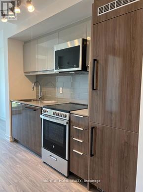 Toronto (Birchcliffe-Cliffside) condo for rent - A modern kitchen with wooden cabinets and a stainless steel oven.