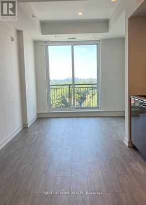 Toronto (Birchcliffe-Cliffside) condo for rent - A room with a large window and a balcony overlooking a green area.
